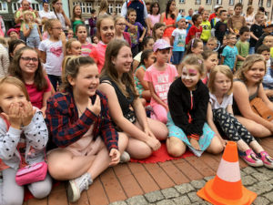 tłum dzieci Crazy Kids siedzący na Rynku z uśmiechniętymi buźkami