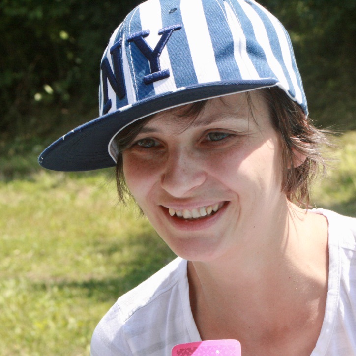 uśmiechnięta kobieta z uśmiechem na twarzy z czapeczką w biało-niebieskie paski