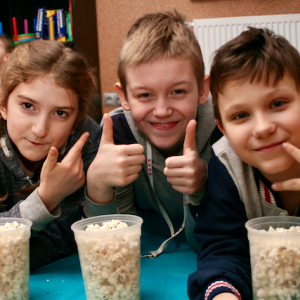 Chłopcy jedzą popcorn na Dziecięcym Klubie Wideo